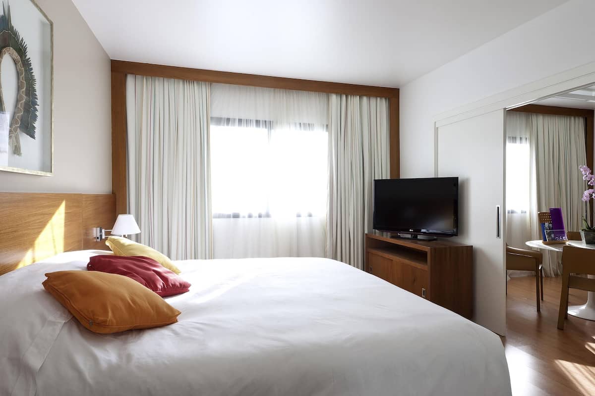 A hotel room with a bed, a TV, a desk, and a chair.