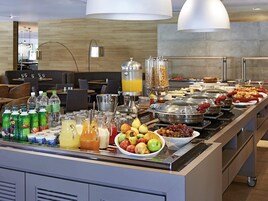 Un bufé con diversos alimentos, bebidas y un dispensador de zumo.