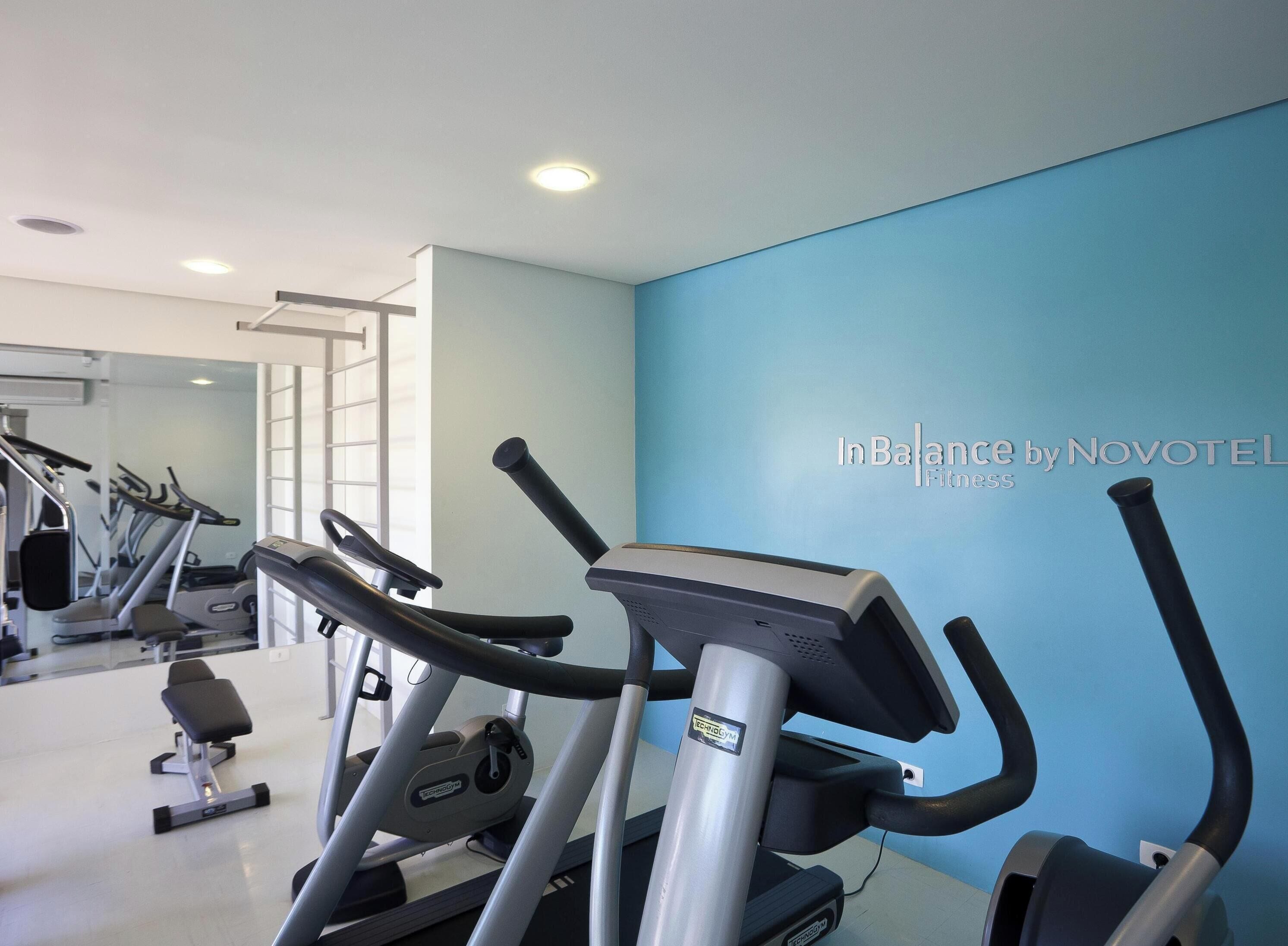 Ett gym med löpband och annan träningsutrustning, en spegel och en blå vägg.