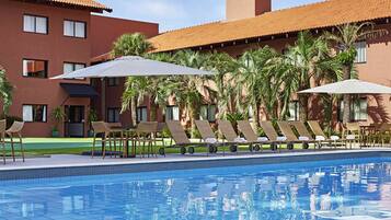 Una piscina al aire libre, sillones reclinables de piscina