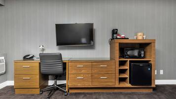Un espacio de oficina moderno con un escritorio de madera, una silla de oficina negra y un televisor montado.