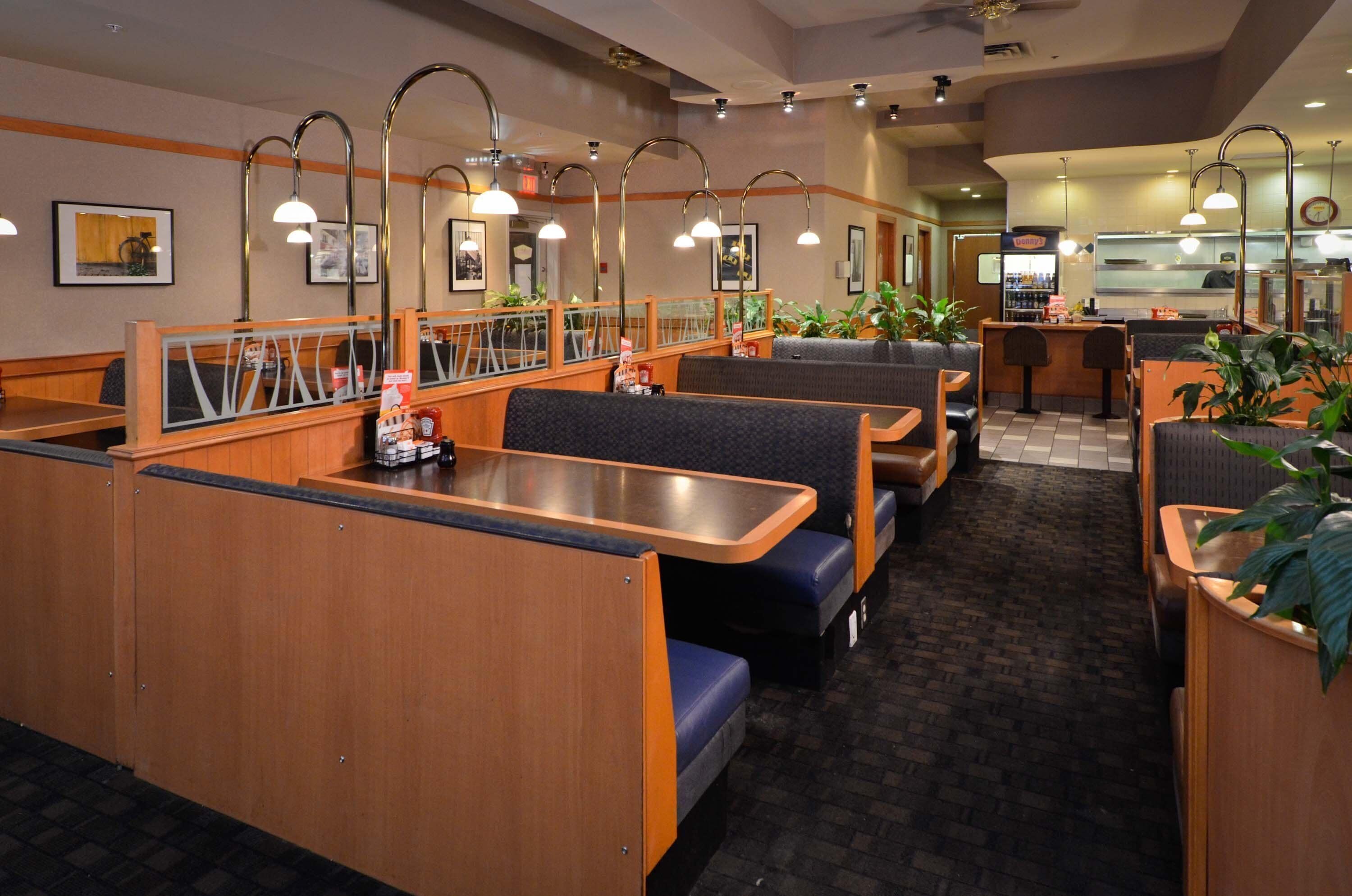 A restaurant with booths and tables, wooden counters, and overhead lighting.