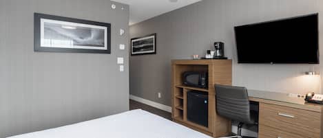 Une chambre d’hôtel équipée d’un lit, d’un bureau avec un ordinateur, d’une télévision et d’un four à micro-ondes.