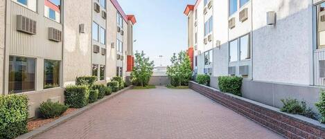 A pathway leading to a building with multiple windows and air conditioning units.