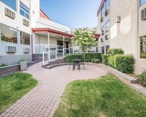 A courtyard with a paved walkway, a small seating area with chairs, and a tree. - Quality Inn & Conference Centre Red Deer - 50th Avenue (Red Deer)