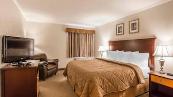 Quarto de hotel com uma cama, televisão, escrivaninha, cadeira e abajur.