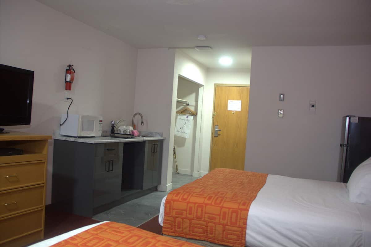 Une chambre d’hôtel comprenant un lit, un bureau avec un micro-ondes, une petite kitchenette et un placard.