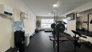 Een sportschool met fitnessapparatuur, een waterfontein en een raam met uitzicht op buiten.