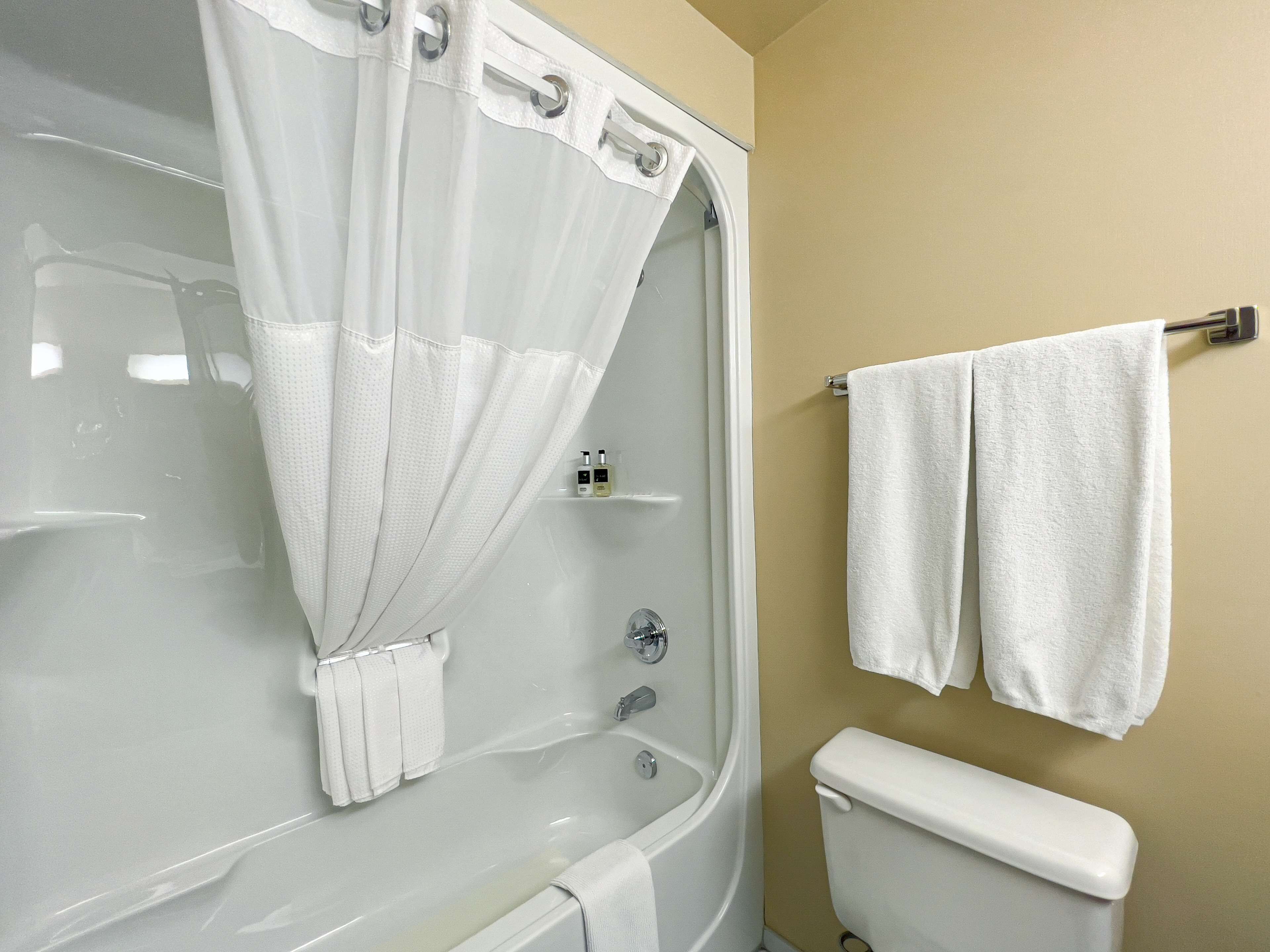 A bathroom with a bathtub, a toilet, and a towel rack with two towels.