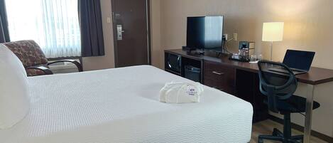 Habitación de hotel con una cama grande, un escritorio con una computadora portátil, un televisor y una silla.