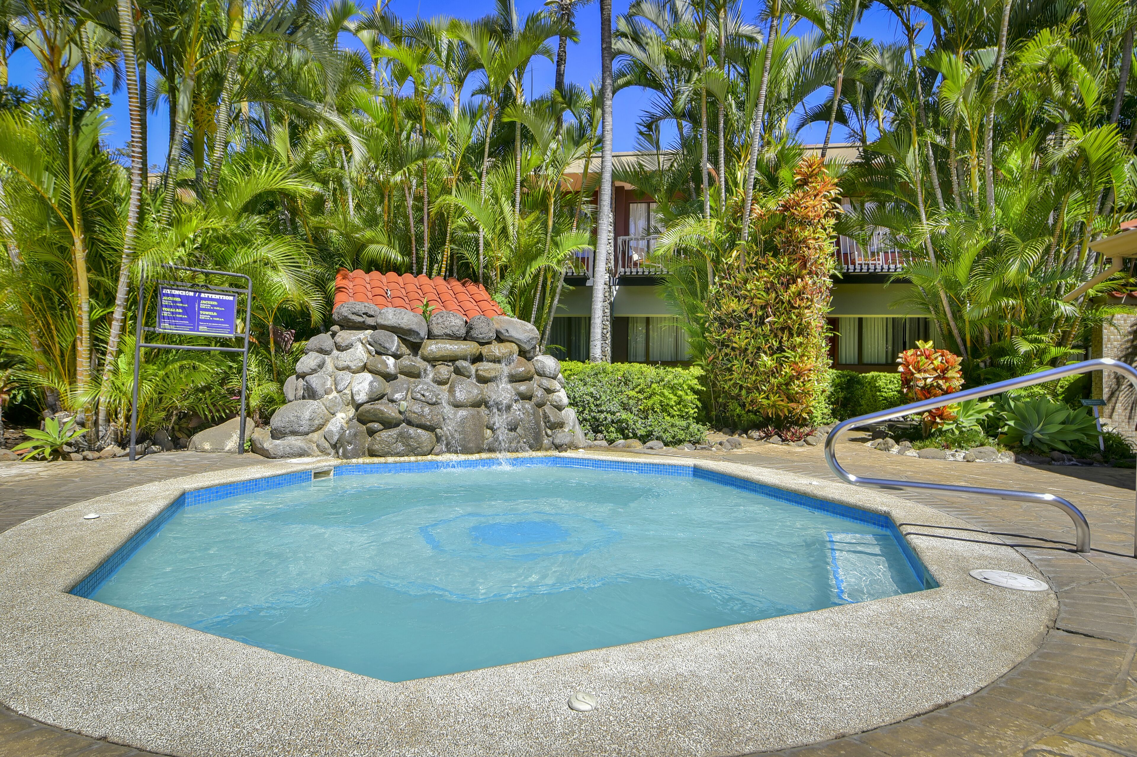Una piscina rodeada de vegetación tropical y un muro de piedra.