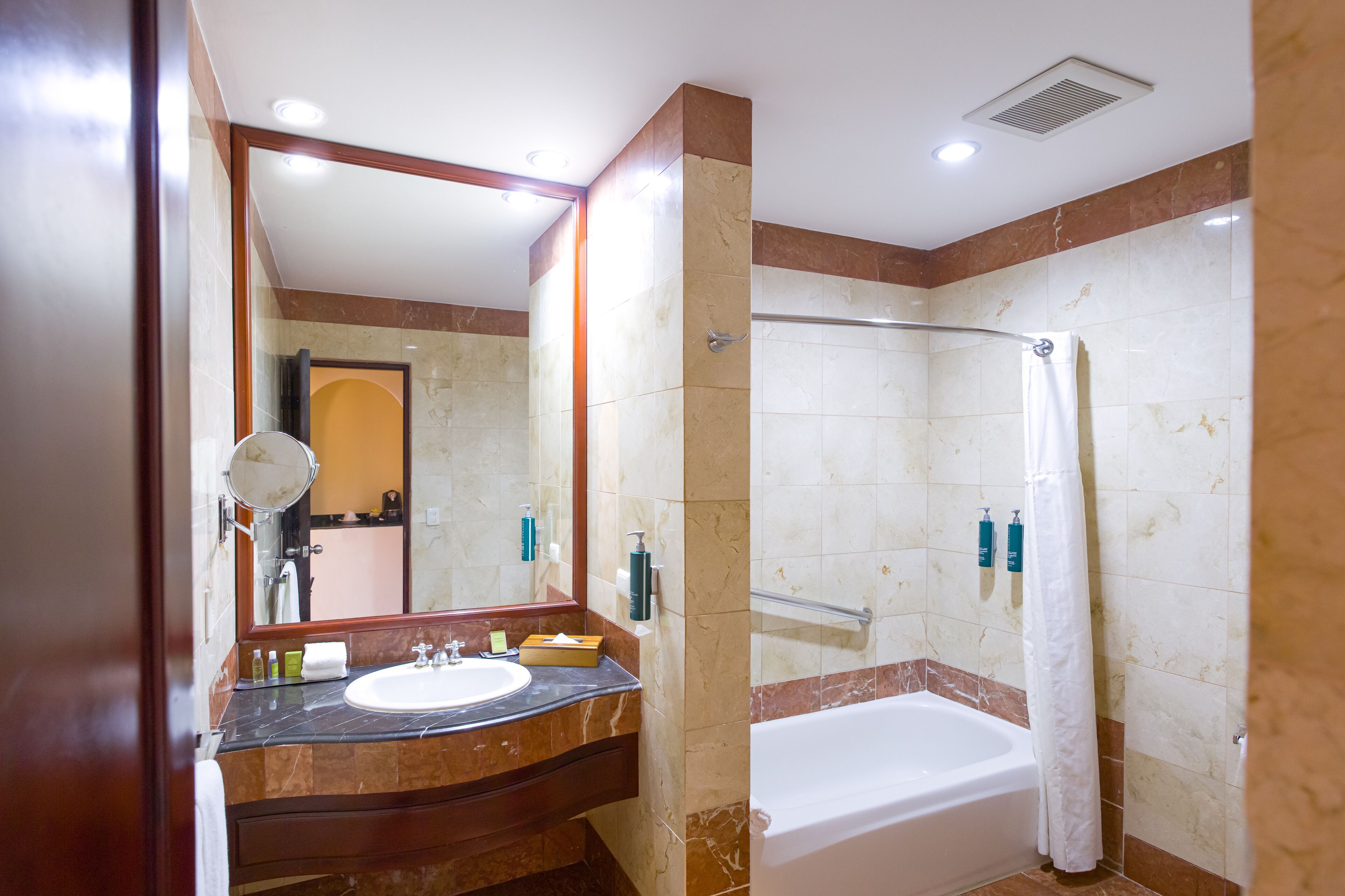 Un baño con lavamanos de mármol, bañera y ducha con puerta de vidrio.