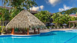 A swimming pool with lounge chairs and a thatched gazebo. - DoubleTree by Hilton Cariari - San Jose Costa Rica (La Asunción)