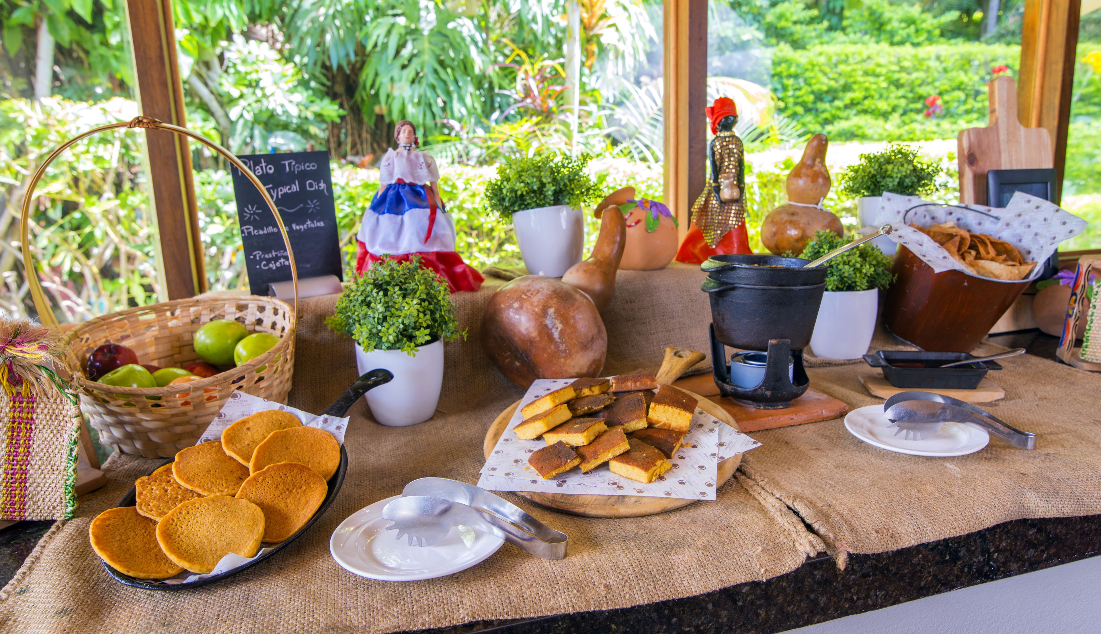 A table with food items, a basket of fruits, and decorative objects.