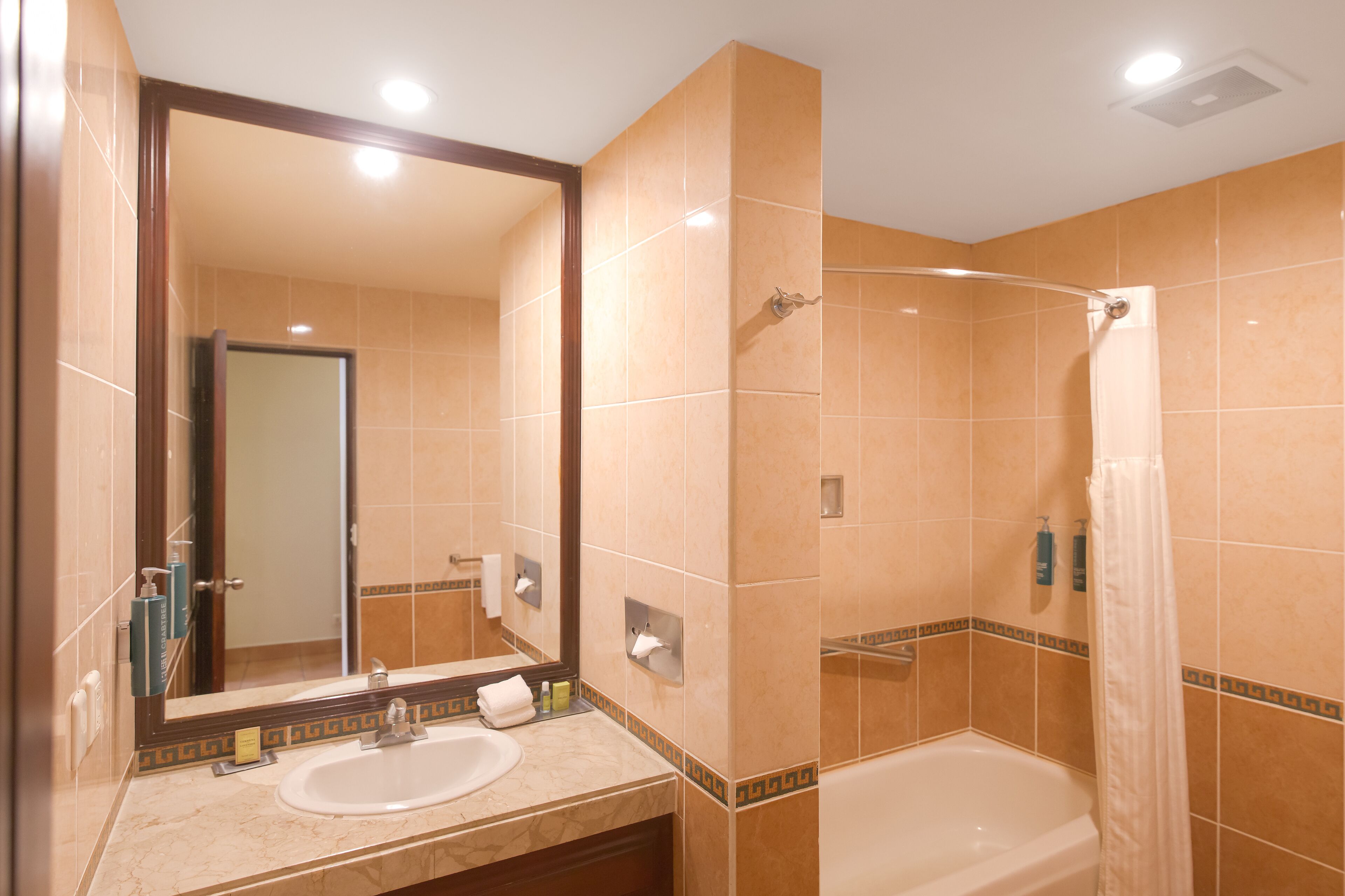 A bathroom with a sink, mirror, shower, and bathtub.
