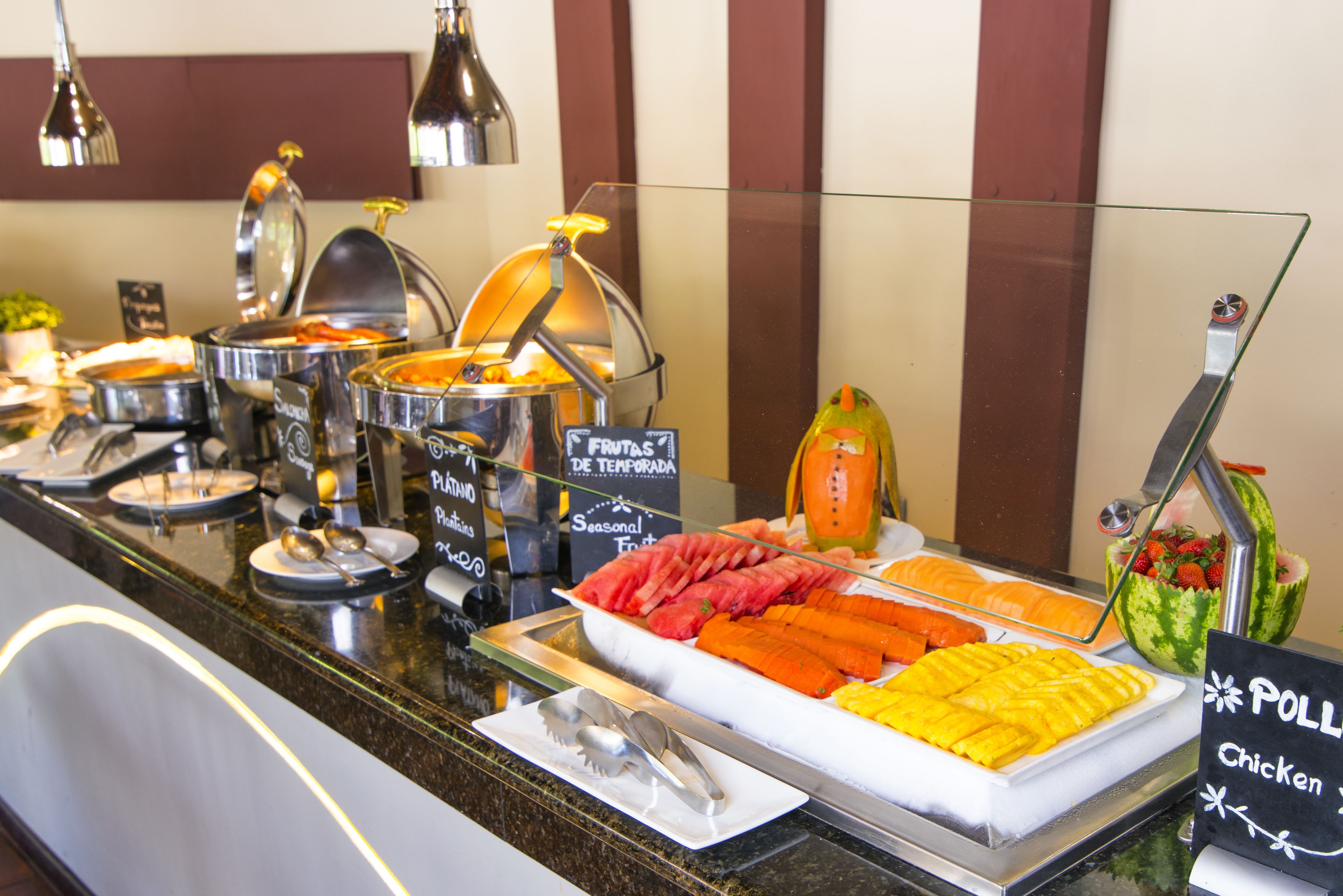 A buffet with various food options including fruits, vegetables, and a sign indicating pollard chicken.