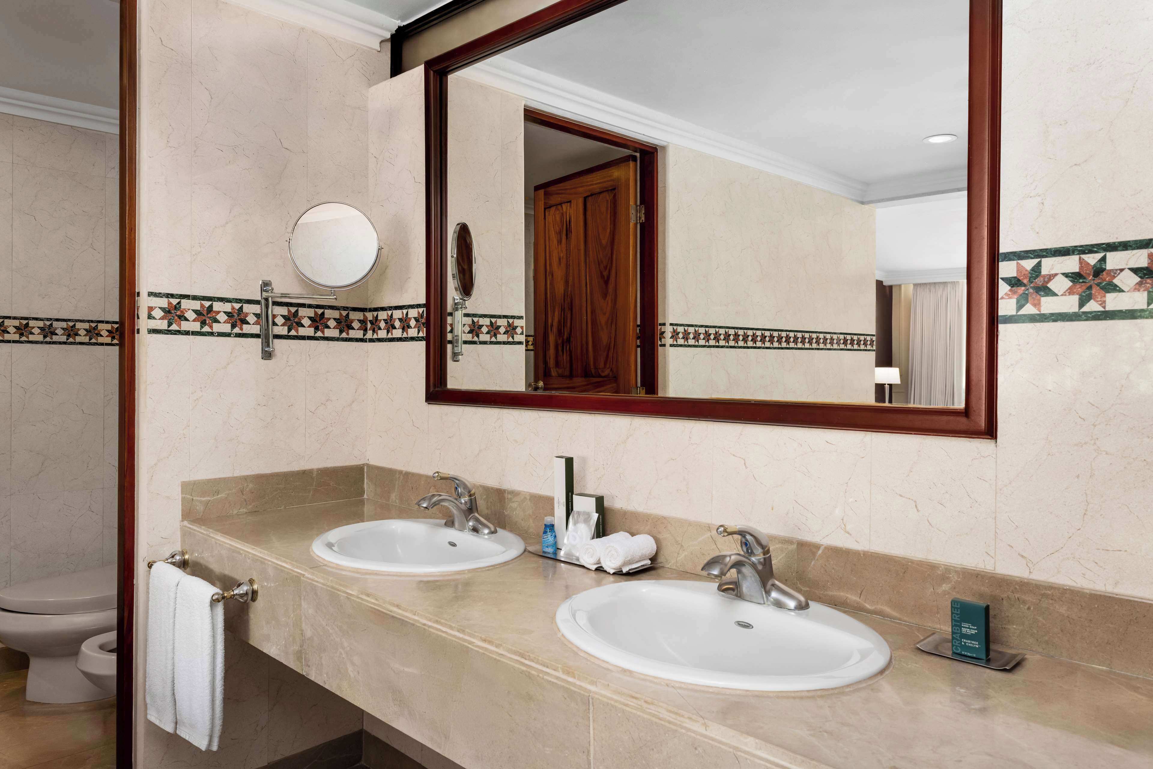 A bathroom with two sinks, a mirror, and a toilet.