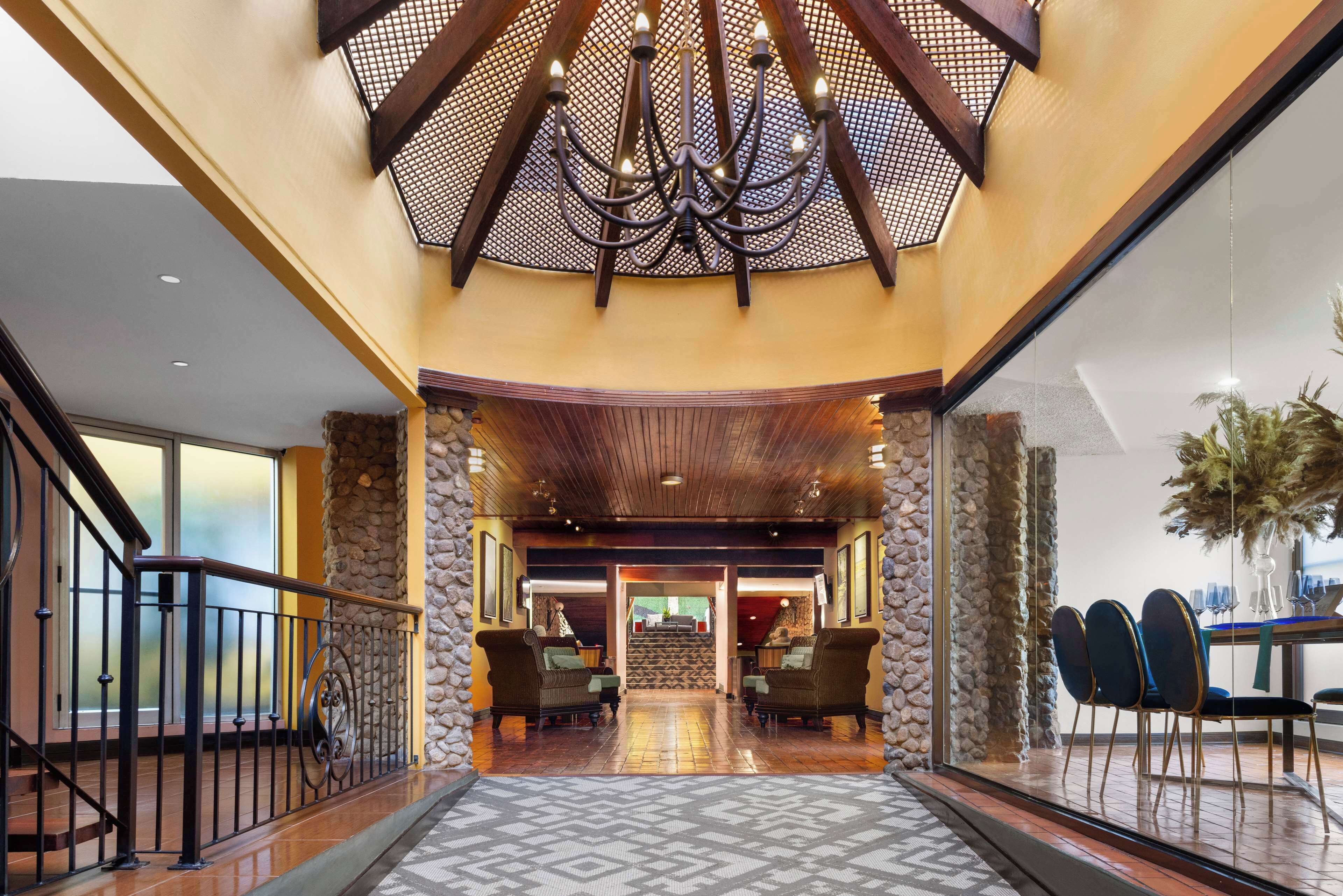 A lobby with a chandelier, stone walls, and a staircase leading to upper floors.
