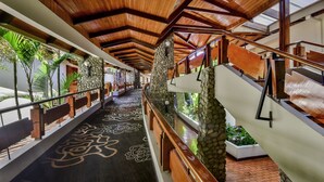 A corridor with a wooden ceiling, stone pillars, and a patterned floor. - DoubleTree by Hilton Cariari - San Jose Costa Rica (La Asunción)