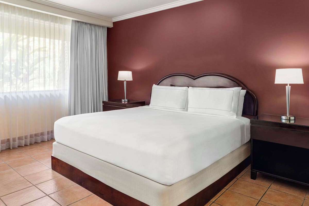 A neatly made bed with white linens, a dark wooden headboard, and two bedside lamps.