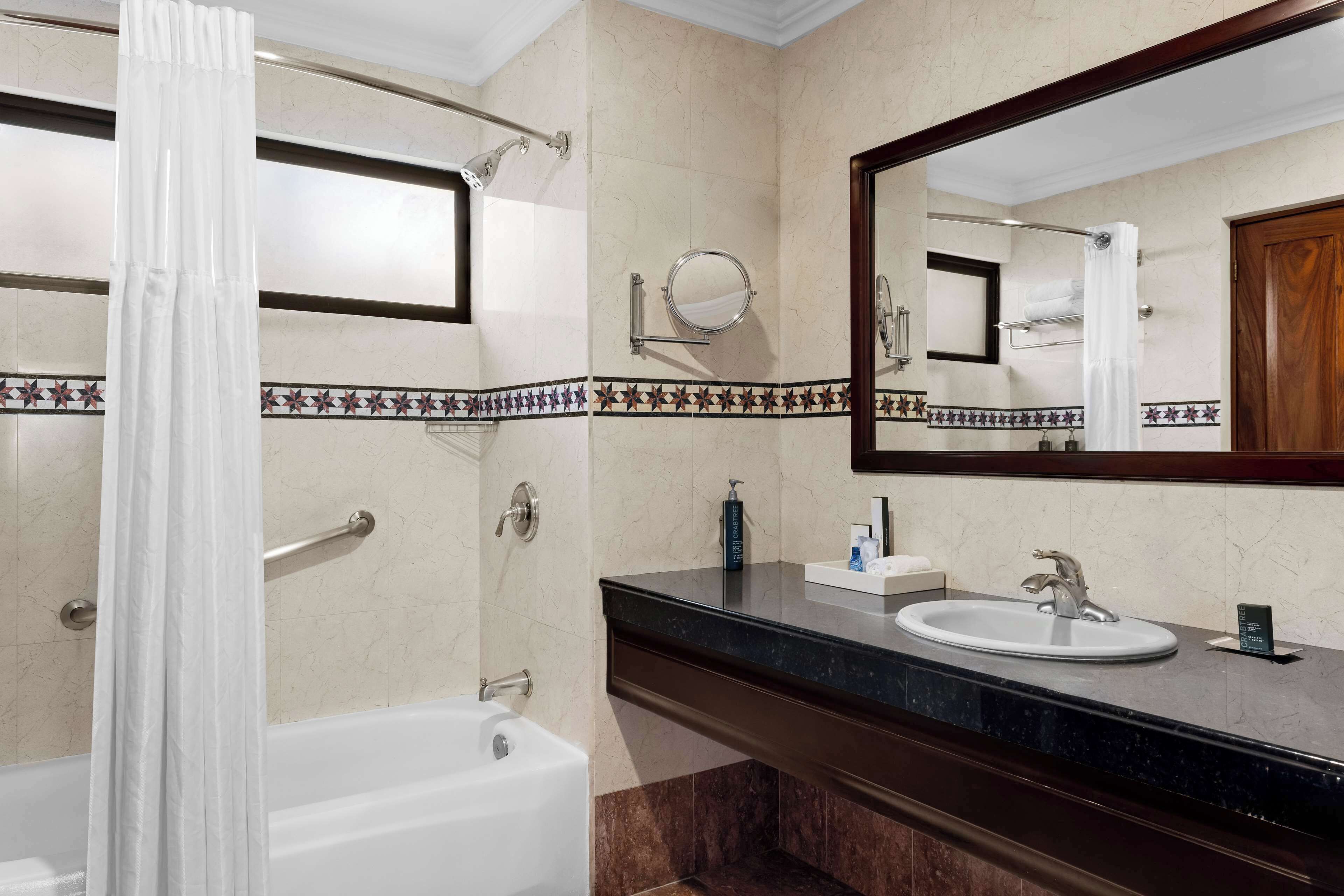 Une salle de bain avec une baignoire, un lavabo, un miroir et un rideau de douche.