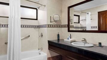 Une salle de bain avec une baignoire, un lavabo, un miroir et un rideau de douche.