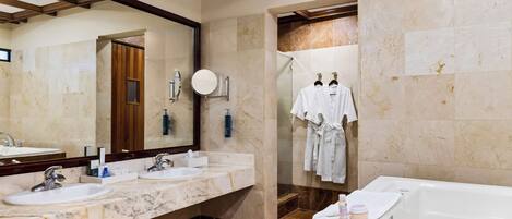 A modern bathroom with two sinks, a large mirror, a bathtub, and a shower area.