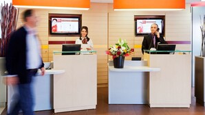 Een receptie met twee balies, een groot scherm met informatie en een bloemenvaas.