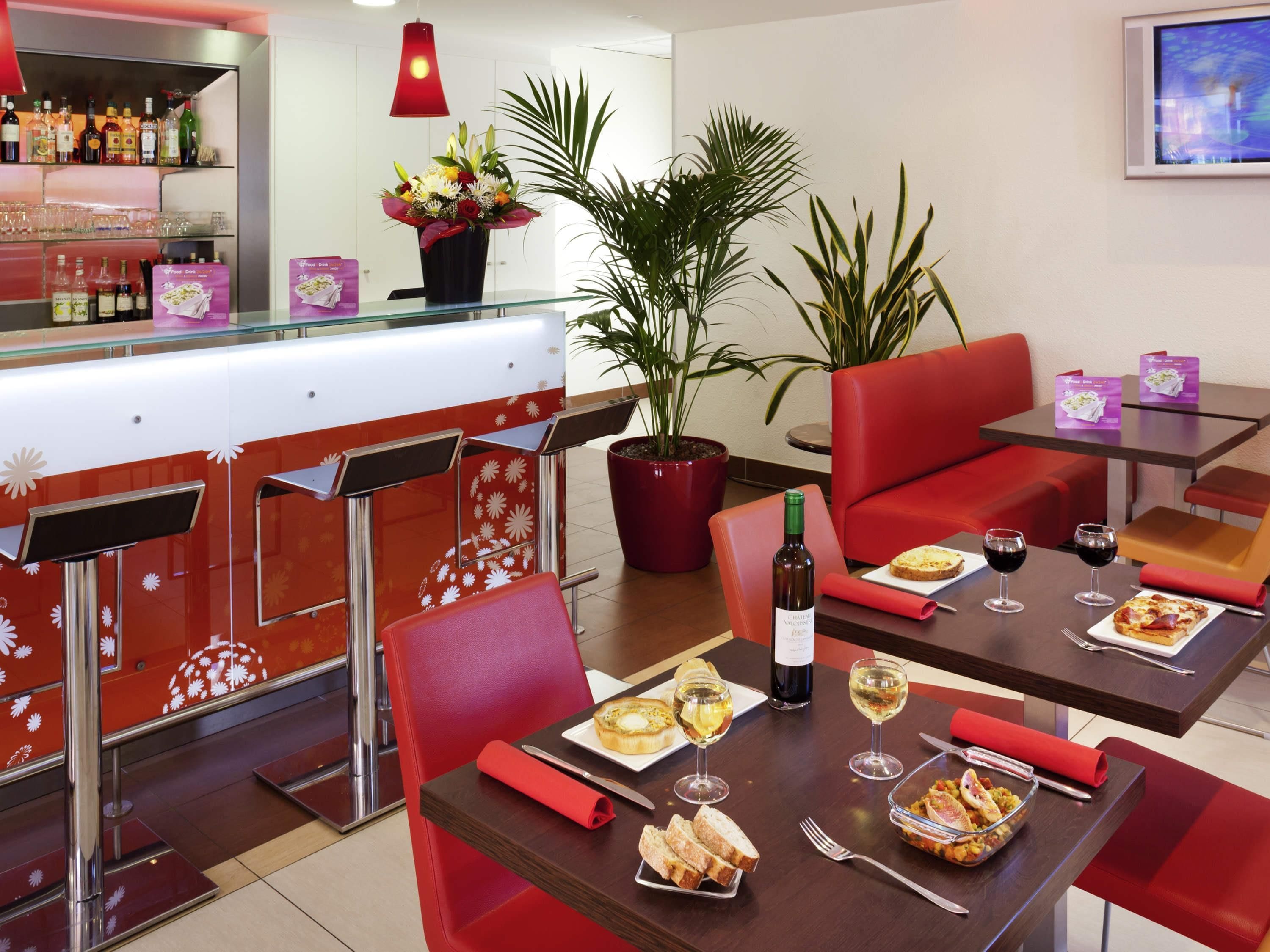 A restaurant interior with red seating, a bar area, and a potted plant.