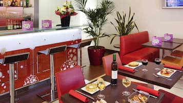 A restaurant interior with red seating, a bar area, and a potted plant.
