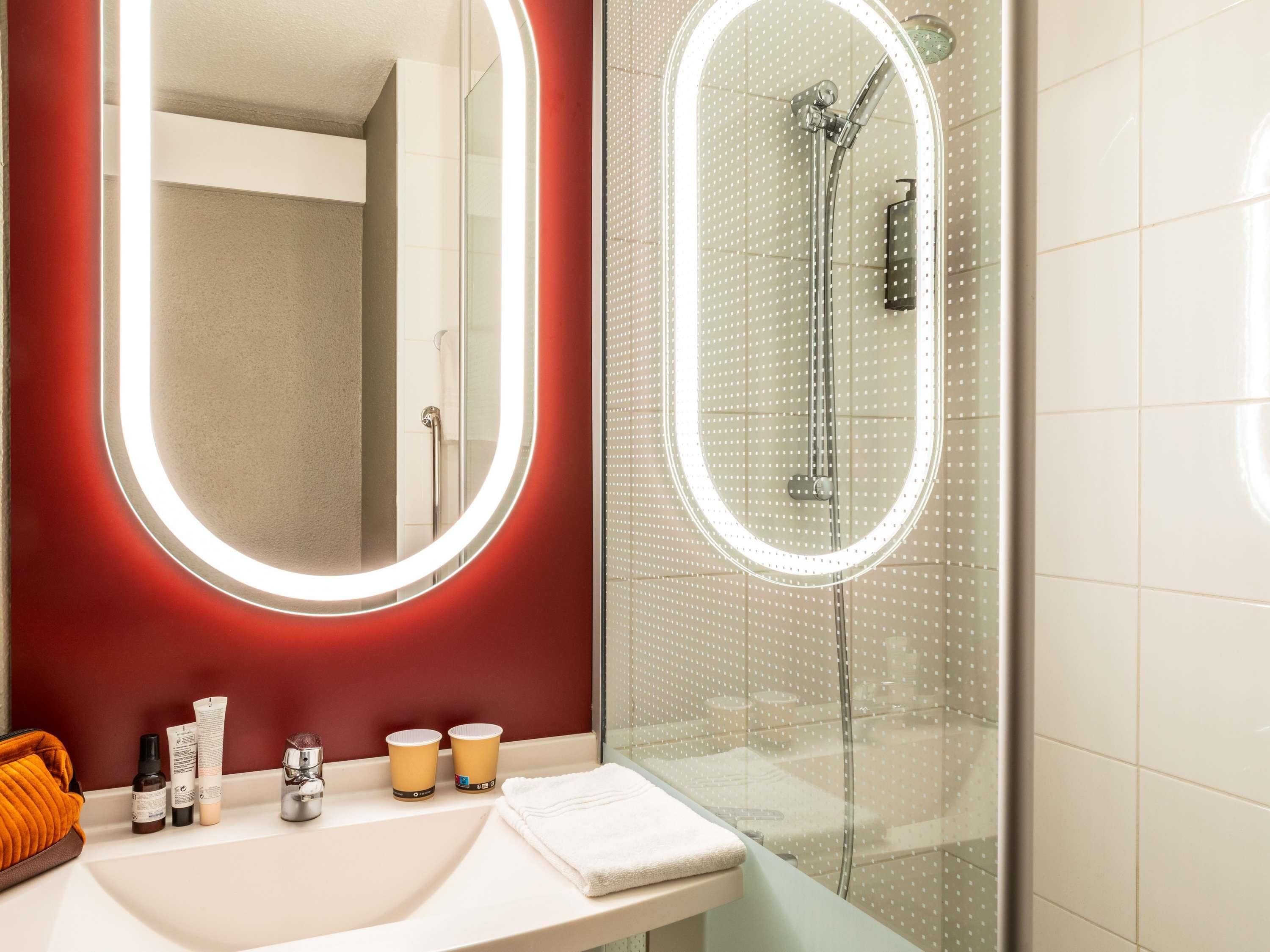 Une salle de bain avec un miroir, une douche et des articles de toilette sur le comptoir.