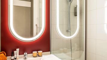 Une salle de bain avec un miroir, une douche et des articles de toilette sur le comptoir.