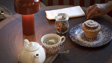 Una mesa con un calentador de agua, una taza de té, un muffin y una vela.