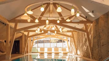 Interior de madera con una piscina de fondo de cristal que refleja la estructura del techo.