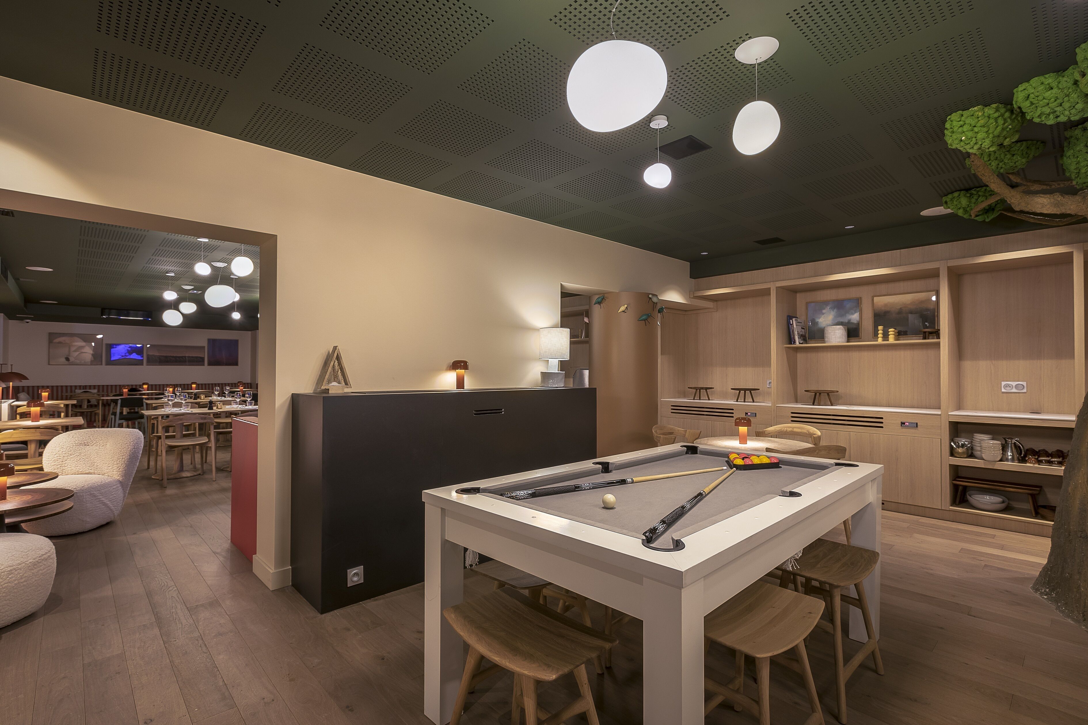 A modern indoor pool area with a pool table, bar stools, and a seating area with chairs.