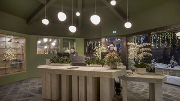 A reception desk with a computer, potted plants, and a view of the snowy outdoors.