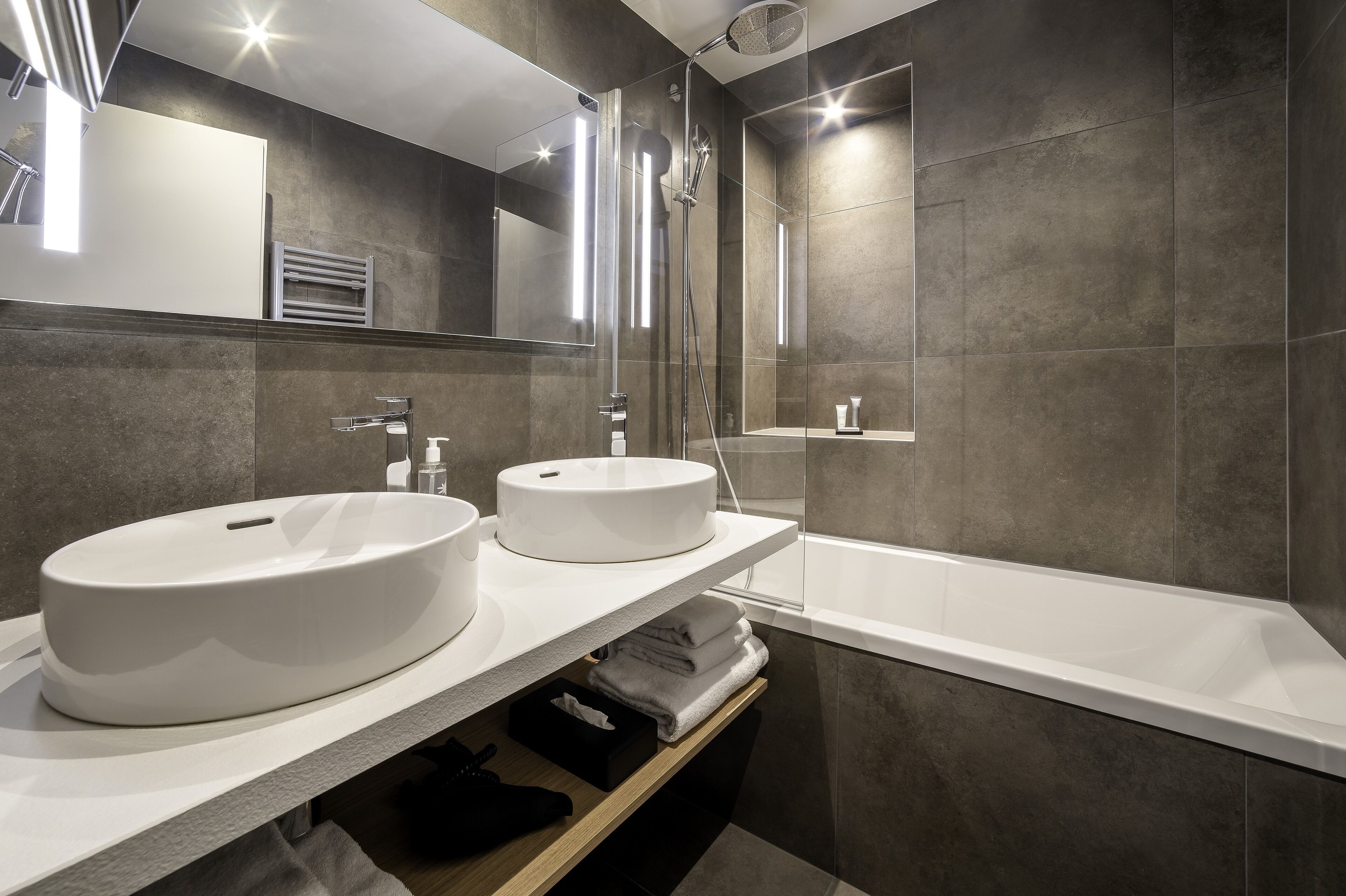 A modern bathroom with two sinks, a shower, and a bathtub.