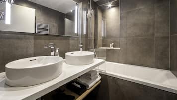 A modern bathroom with two sinks, a shower, and a bathtub.