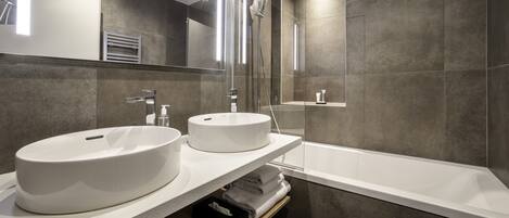 A modern bathroom with two sinks, a shower, and a bathtub.