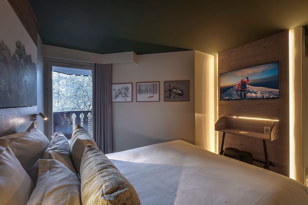 Une chambre d’hôtel avec un lit, une grande fenêtre et des œuvres d’art accrochées au mur.