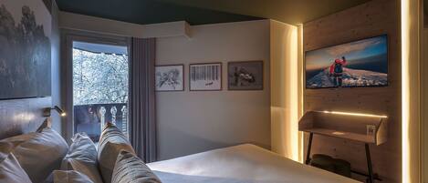 A hotel room with a bed, a large window, and artwork on the wall.