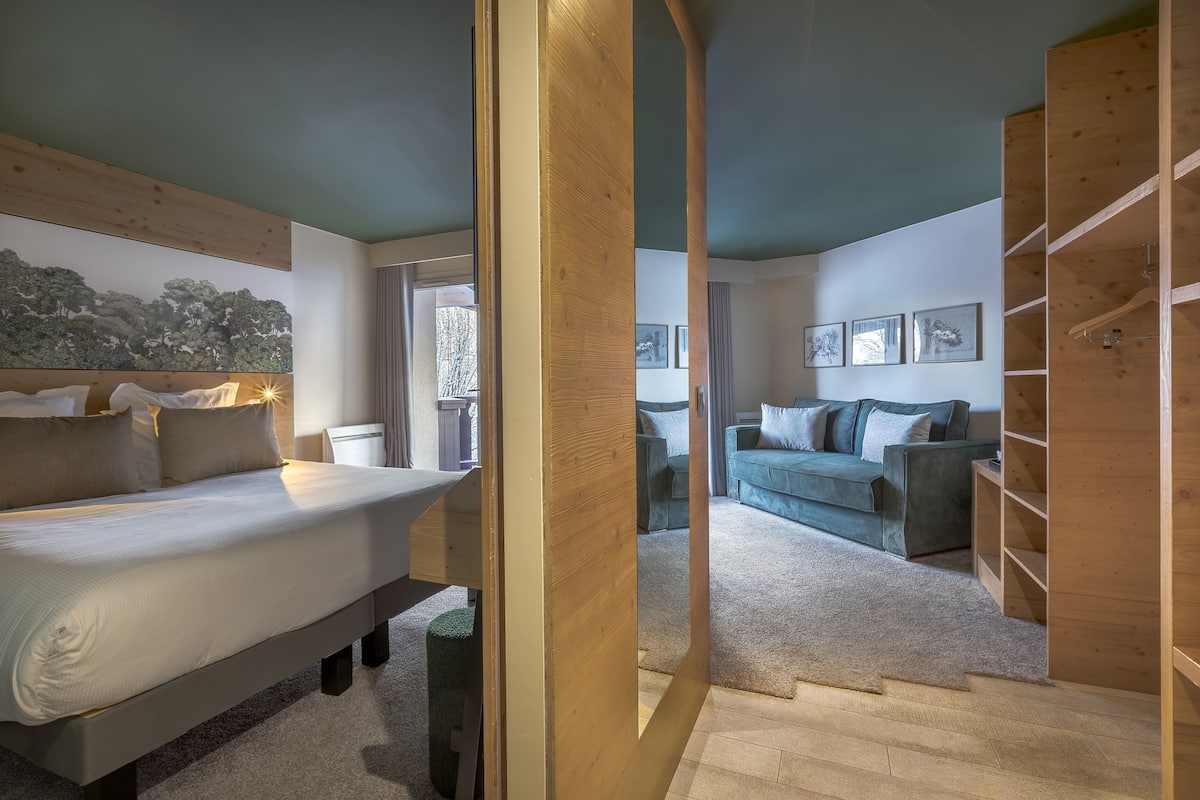 Une chambre à coucher moderne avec un grand lit, une armoire en bois et un canapé vert.