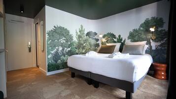 A bedroom with a bed, a nightstand, a wall mural, and a door.