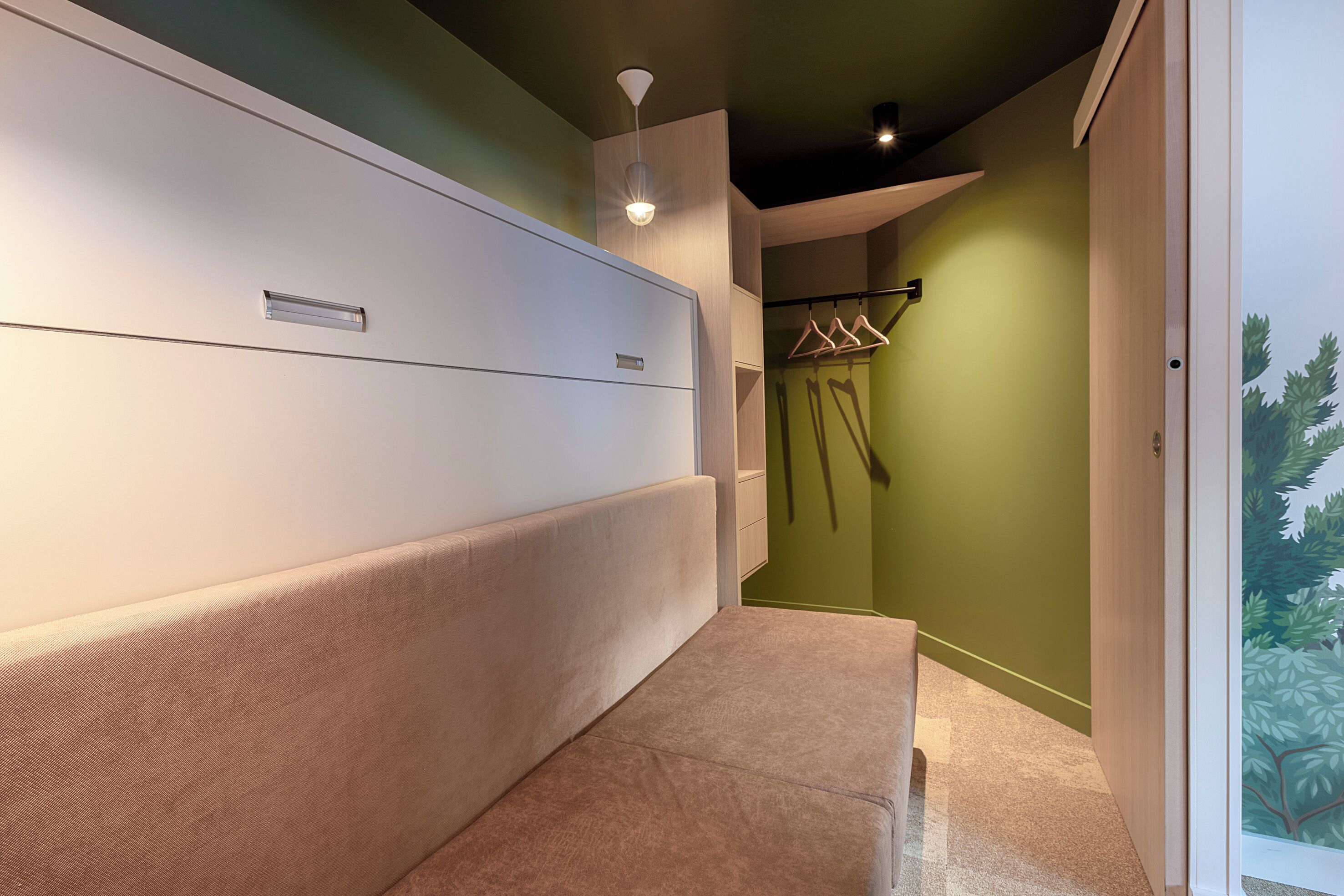 A hallway with a beige sofa, a white cabinet, and a green wall.