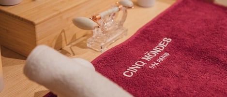 Un ambiente de spa con una camilla de madera, una toalla roja y velas.