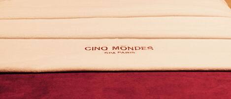 A massage table with a red towel and a white sheet labeled "CINO MONDES SPA PARIS".