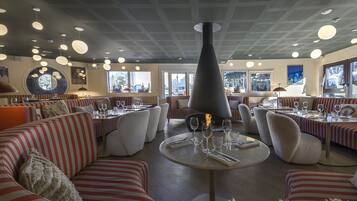 A restaurant with striped seating, round tables, and a central fire feature.
