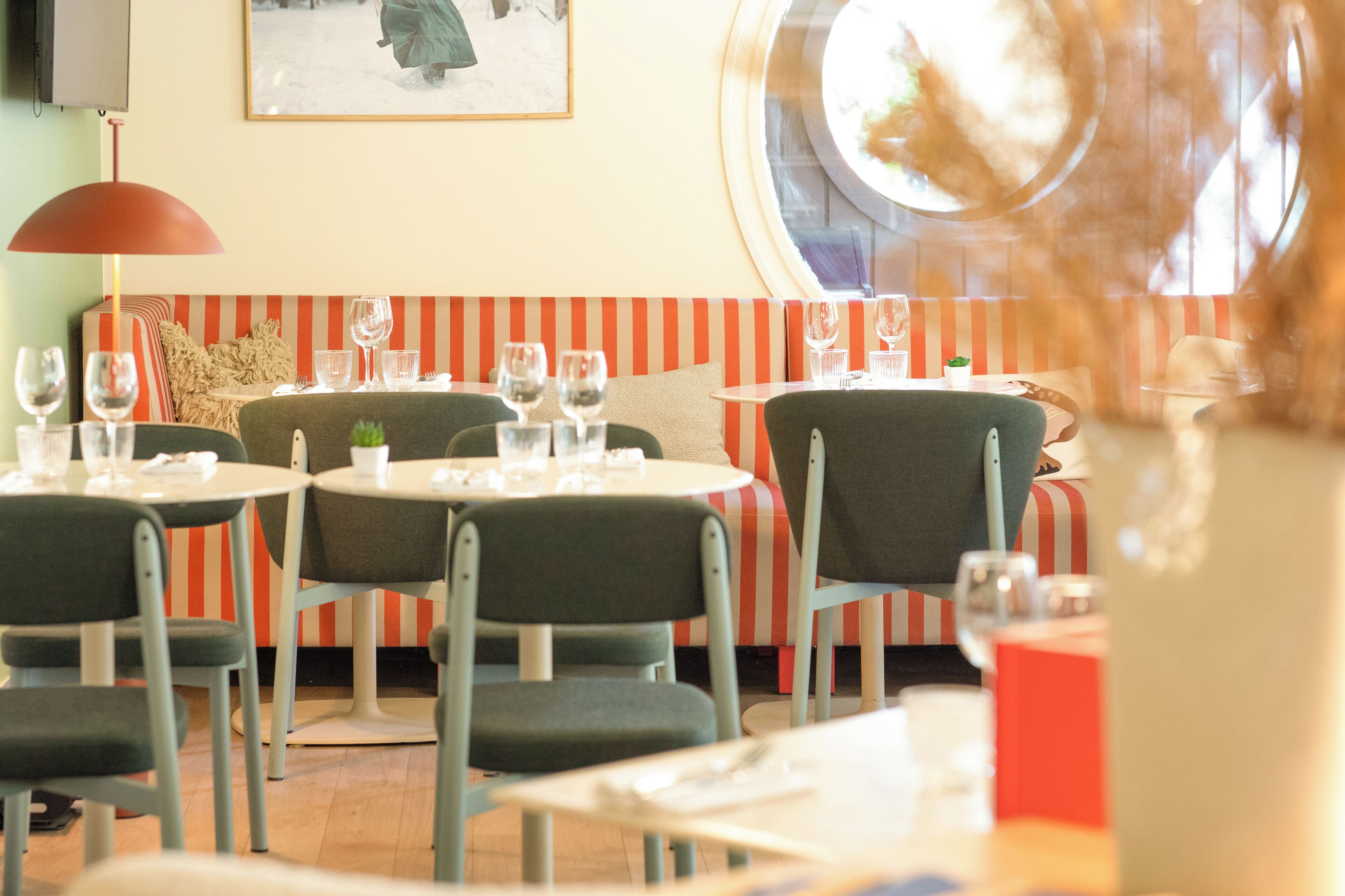 Un ristorante con tavoli rotondi, sedute a righe e vista dalla finestra.