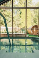 Una piscina interior con vistas a una estructura de madera a través de amplios ventanales.