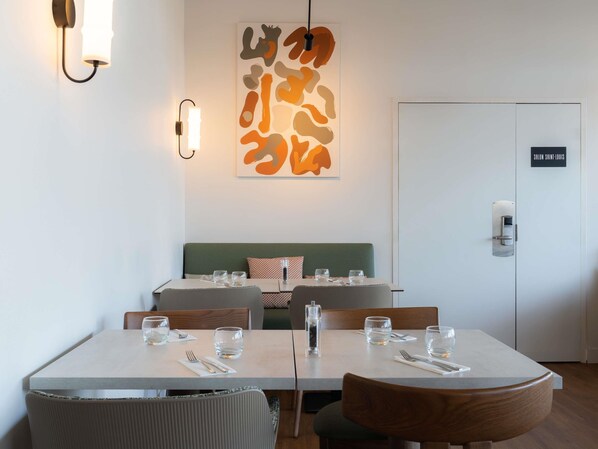 Un comedor moderno con dos mesas, sillas y una lámpara fijada a la pared.